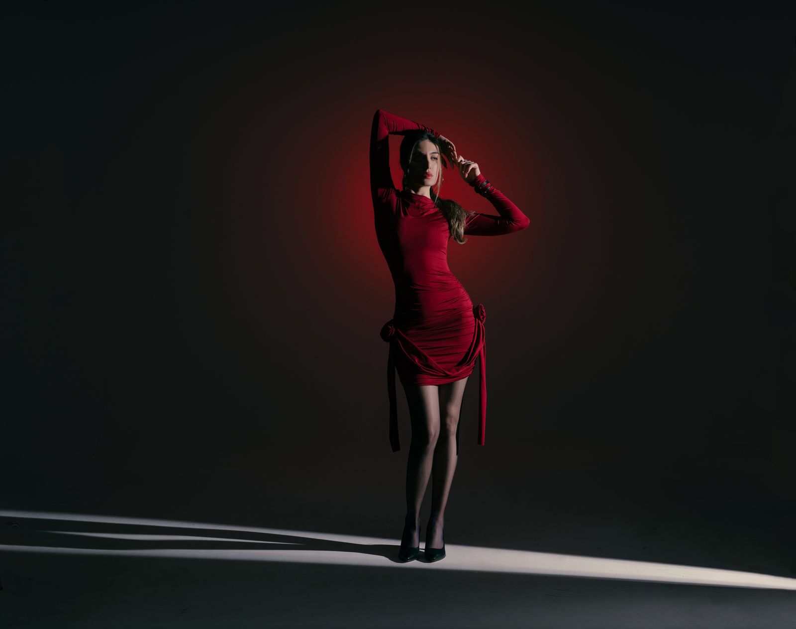 A draped red evening dress under dramatic light